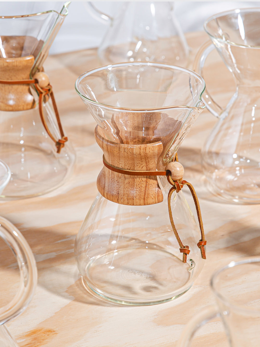 Chemex coffeemakers lined up on a wooden table 