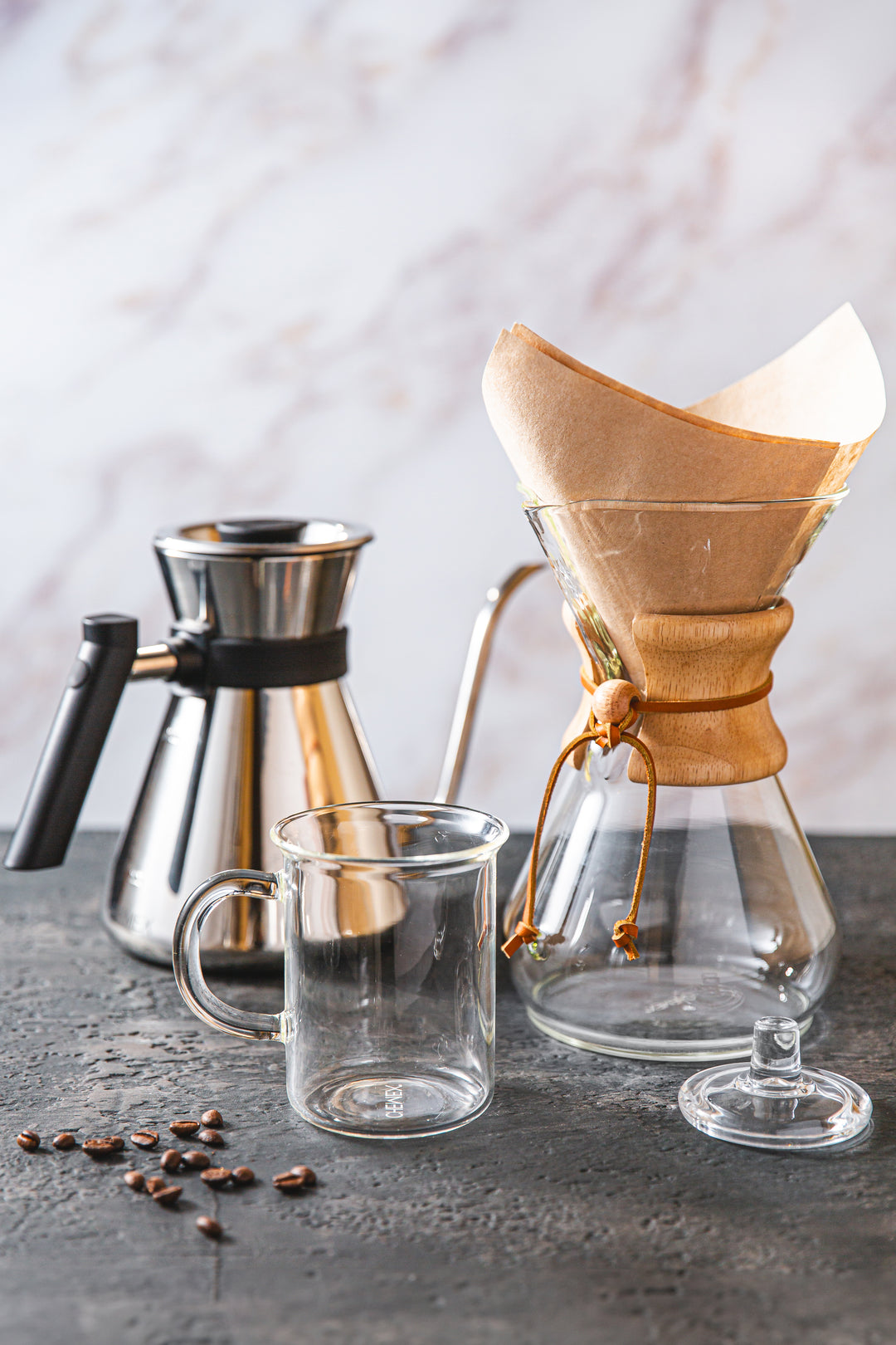 Chemex Chettle, Murray mug 8-cup classic coffeemaker with a natural square filter and the glass lid on a grey concrete counter top