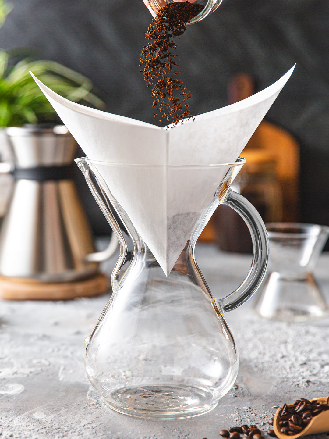 Pouring coffee grounds into a white square filter
