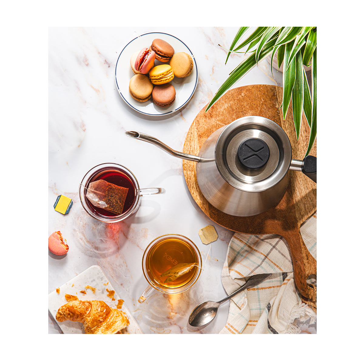 Tea-making setup with a teapot, cup, and cookies on a marble surface.