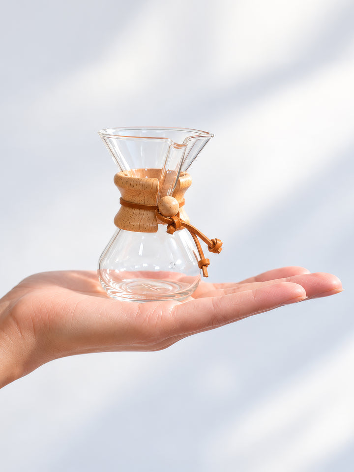 The CHEMEX Ornament, an exactly replica of the CHEMEX six-cup Classic but at 4" tall. The ornament is sitting in the palm of a persons hand.