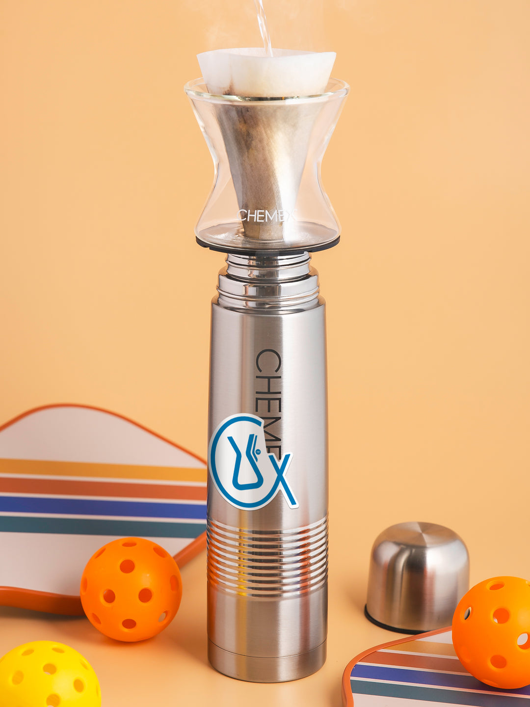 Chemex CX Symbol Sticker on a thermos, surrounded by pickle ball equipment 