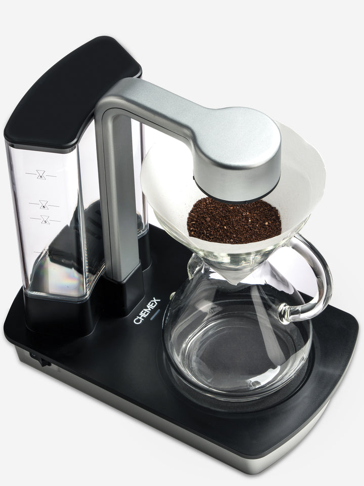 Ottomatic 2.0 with the eight cup glass handle chemex, camera view is looking down on the coffeemaker filter which is full of grounds. 